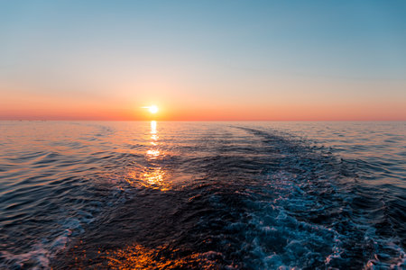 Sunset in the sea and a trace from the shipの写真素材