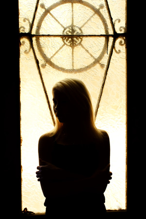 Beautiful young blonde girl. Dramatic portrait of a woman in the dark. Dreamy female look in twilight. Female silhouette in the shadows.の写真素材