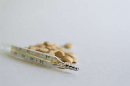 close-up shot of pills and medical mercury thermometers