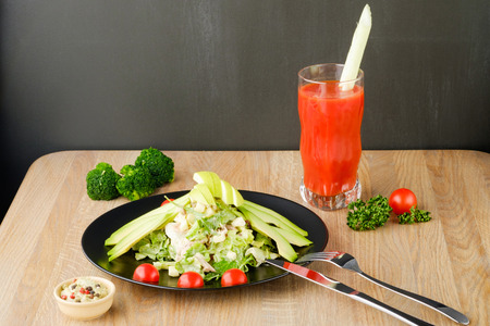 salad served on a black plate with tomato juiceの写真素材