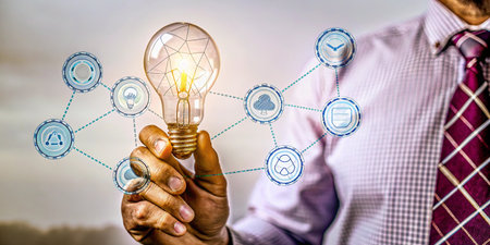 Businessman holding a lightbulb with a network of icons aroundの写真素材
