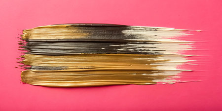 Strokes of gold paint on a pink background close-up