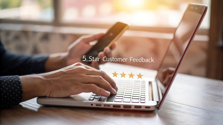 Customer reviews concept. Businessman hand using smart phone and laptop computer with 5 star rating on screen.の写真素材