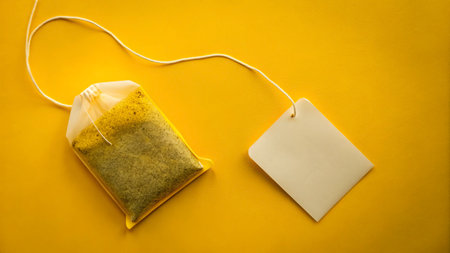 Tea bag with blank label on a yellow background. Top view.の写真素材