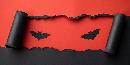 Halloween background with black bats and torn paper on red background.
