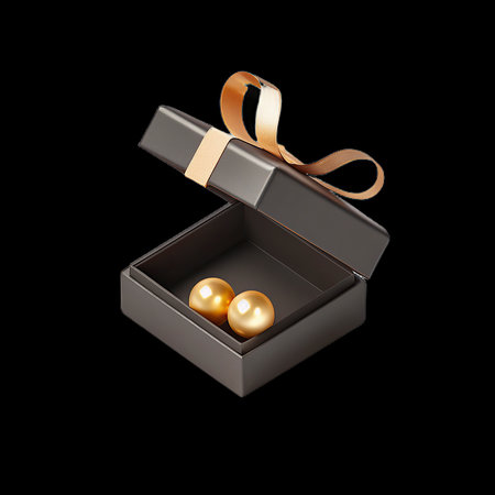 Open black gift box with golden ribbon and pearls isolated on black background