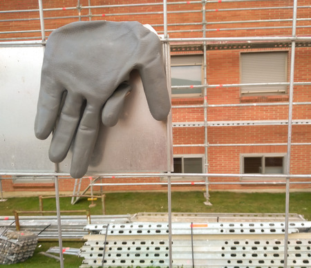 any worker's gray glove in the fence used to build scalfford close to the wall of an old apartments...