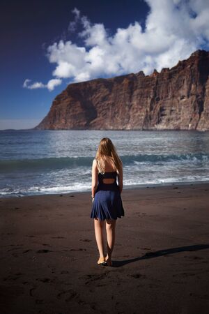Young woman walking on Los Gigantes beach in Tenerifeの写真素材
