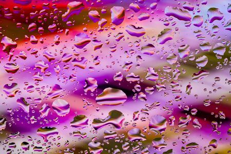 Neon lights behind water drops close up