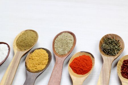 selective focus on Assortment of spices in wooden spoons, white background.の写真素材