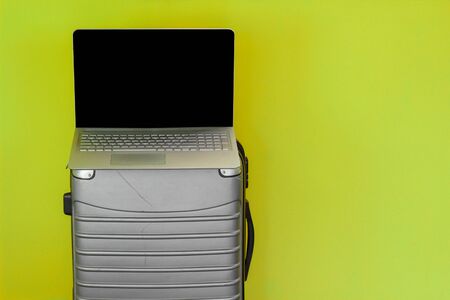 a laptop on a silver travel suitcase, internet and travel concept, green background