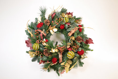 christmas wreath with pine cones and red berries on white backgroundの写真素材