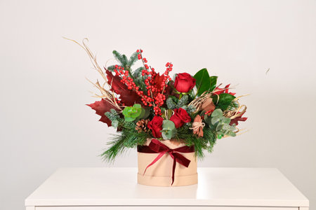 Christmas bouquet of red and green flowers in a gift box on a white backgroundの写真素材