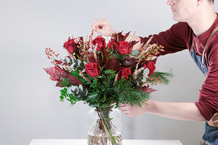Man making a bouquet of red roses in a glass vaseの写真素材
