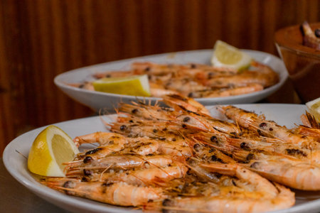 Grilled shrimps with lemon and herbs on a white plateの写真素材