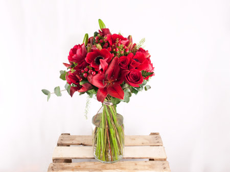 Bouquet of red roses in a vase on a wooden boxの写真素材