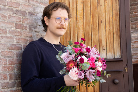Portrait of a handsome young man with a bouquet of flowersの写真素材