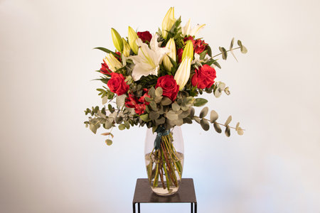 bouquet of flowers with roses and lilies in a vase on a white backgroundの写真素材