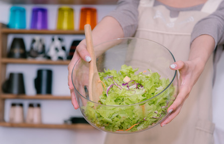 Young woman happy with preparing a good cooking casual lifestyle is mixing salad in kitchen at home. The concept is healthy food.の写真素材