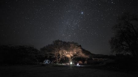 Camp in the wild desert night with milky way on the skyの写真素材