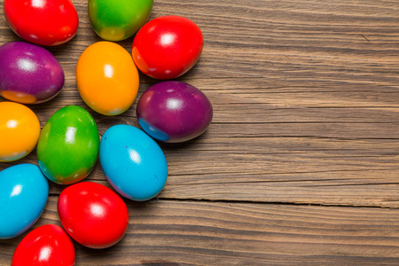 Colored easter eggs on a brown wooden table.の写真素材
