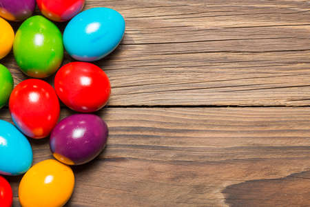 Colored easter eggs on a brown wooden table.の写真素材
