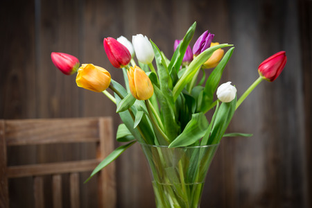 Coloful tulips in a vase on a wooden tableの写真素材