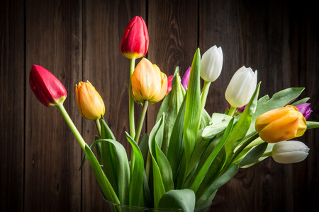 Colorful tulips in a vase on a wooden tableの写真素材