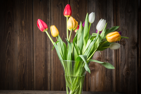 Colorful tulips in a vase on a wooden tableの写真素材