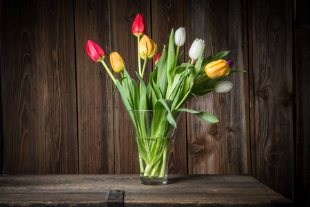 Colorful tulips in a vase on a wooden tableの写真素材