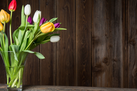 Colorful tulips in a vase on a wooden tableの写真素材