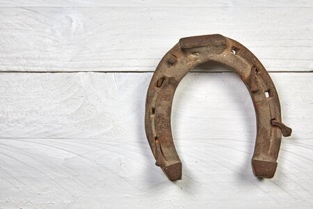 Old rusty horseshoe on a white wooden tableの写真素材