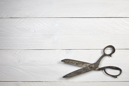 Big old scissors on a white wooden tableの写真素材