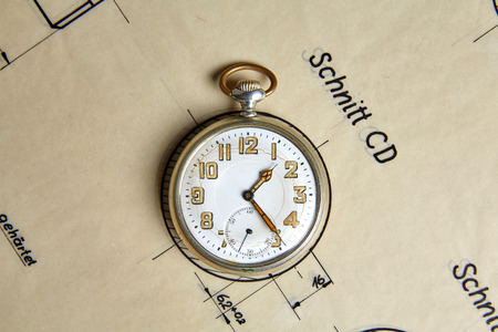 Old pocket watch on old paper on a tableの写真素材