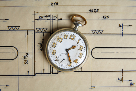 Old pocket watch on old paper on a tableの写真素材