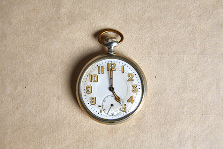 Old pocket watch on old paper on a tableの写真素材