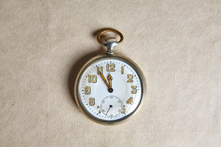 Old pocket watch on old paper on a tableの写真素材