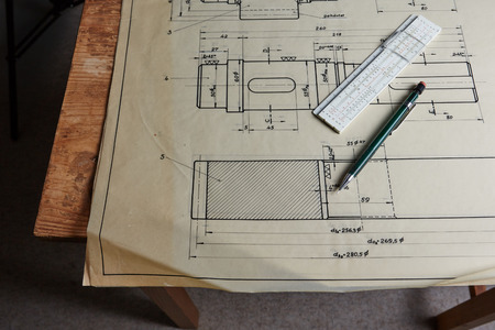 Old technical plan with ruler and pen on old wooden tableの写真素材