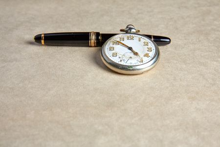 Old pocket watch on old paper on a tableの写真素材