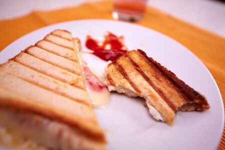 Toast with ham and cheese and ketchup on a kitchen tableの写真素材