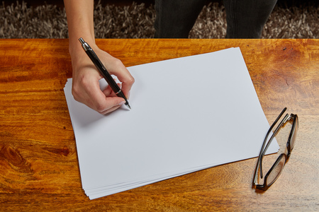 Womans hand writing on a white sheet of paper with a fountain penの写真素材