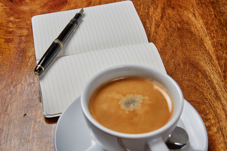 Notepad and coffee on a wooden tableの写真素材