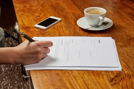 Woman signing a contract in a cafeの写真素材