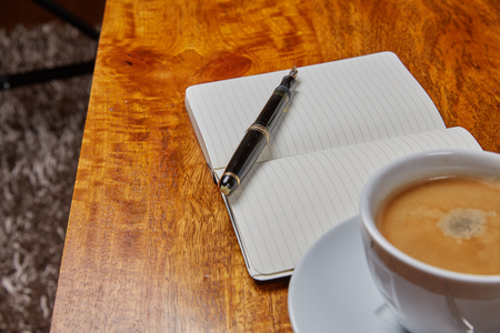 Notepad and coffee on a wooden tableの写真素材