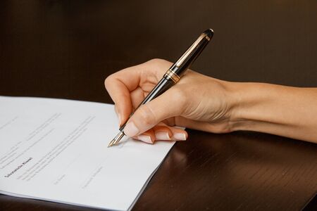 Woman writing on a white sheet of paper, signing a contractの写真素材