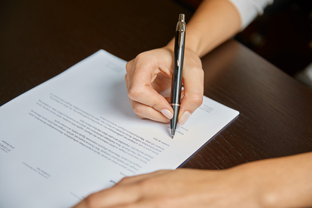 Woman writing on a white sheet of paper, signing a contractの写真素材