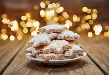 Cinnamon stars on a plate in front of christmas lightsの写真素材