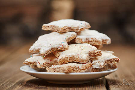 Cinnamon stars on a plate in front of christmas lightsの写真素材