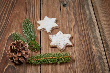 Christmas cinnamon stars and a fir branch on a wooden tableの写真素材