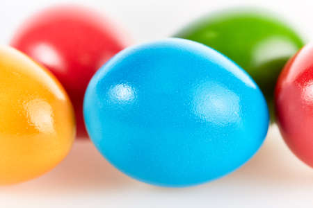 Five colorful easter eggs in different colors lying on white backgroundの写真素材